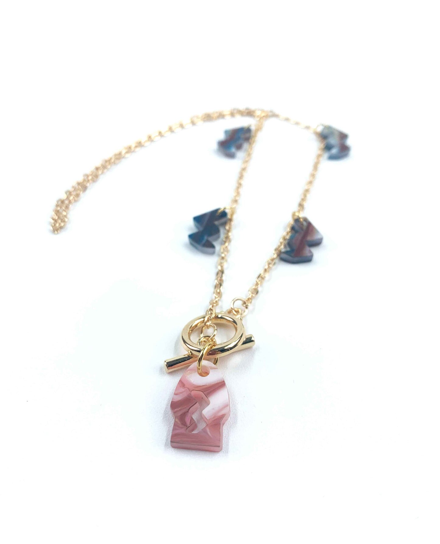 Collar dorado con colgante de resina rosa marmolada y charms geométricos